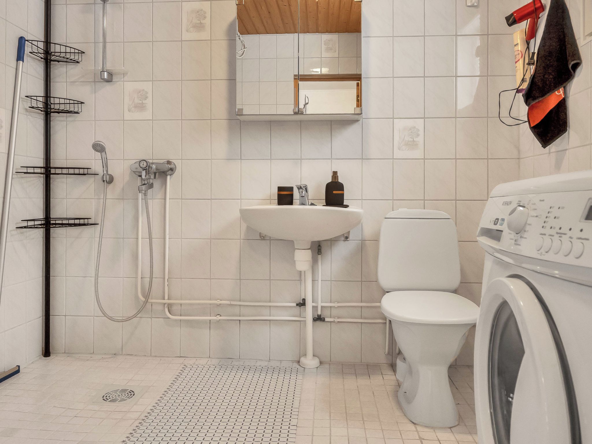 Une salle de bain équipée d’une douche, d’un lavabo, de toilettes et d’un lave-linge.
