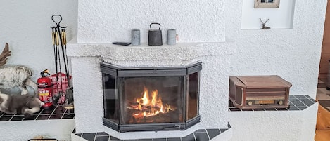 A fireplace with a modern design, a small table, and a decorative item on the wall.