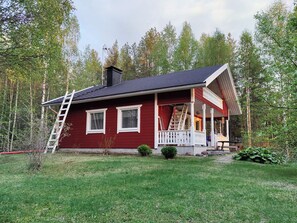 Een rode woning met een veranda, schoorsteen en een ladder.