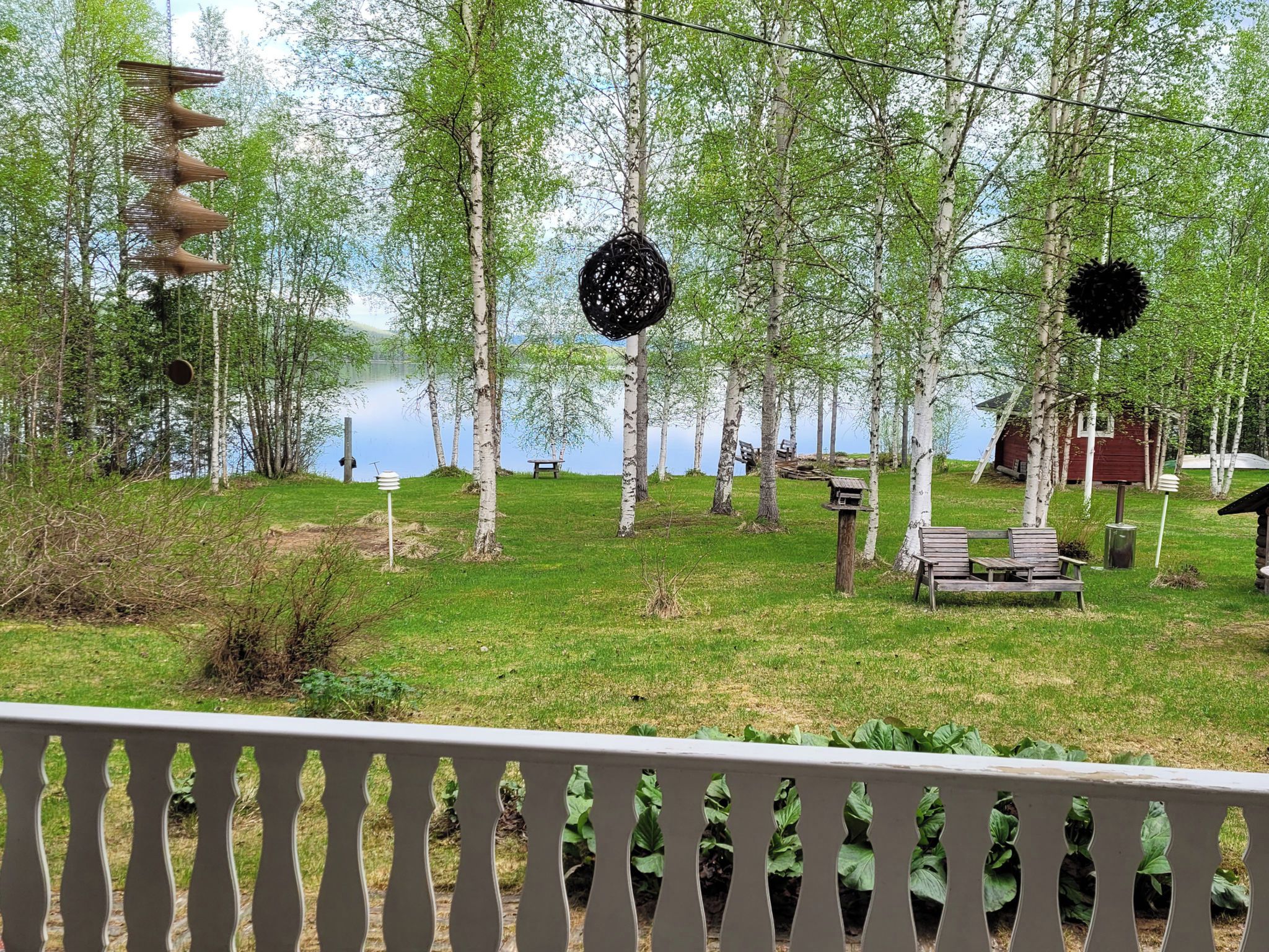 A lakeside property with birch trees, a wooden bench, and a gazebo.
