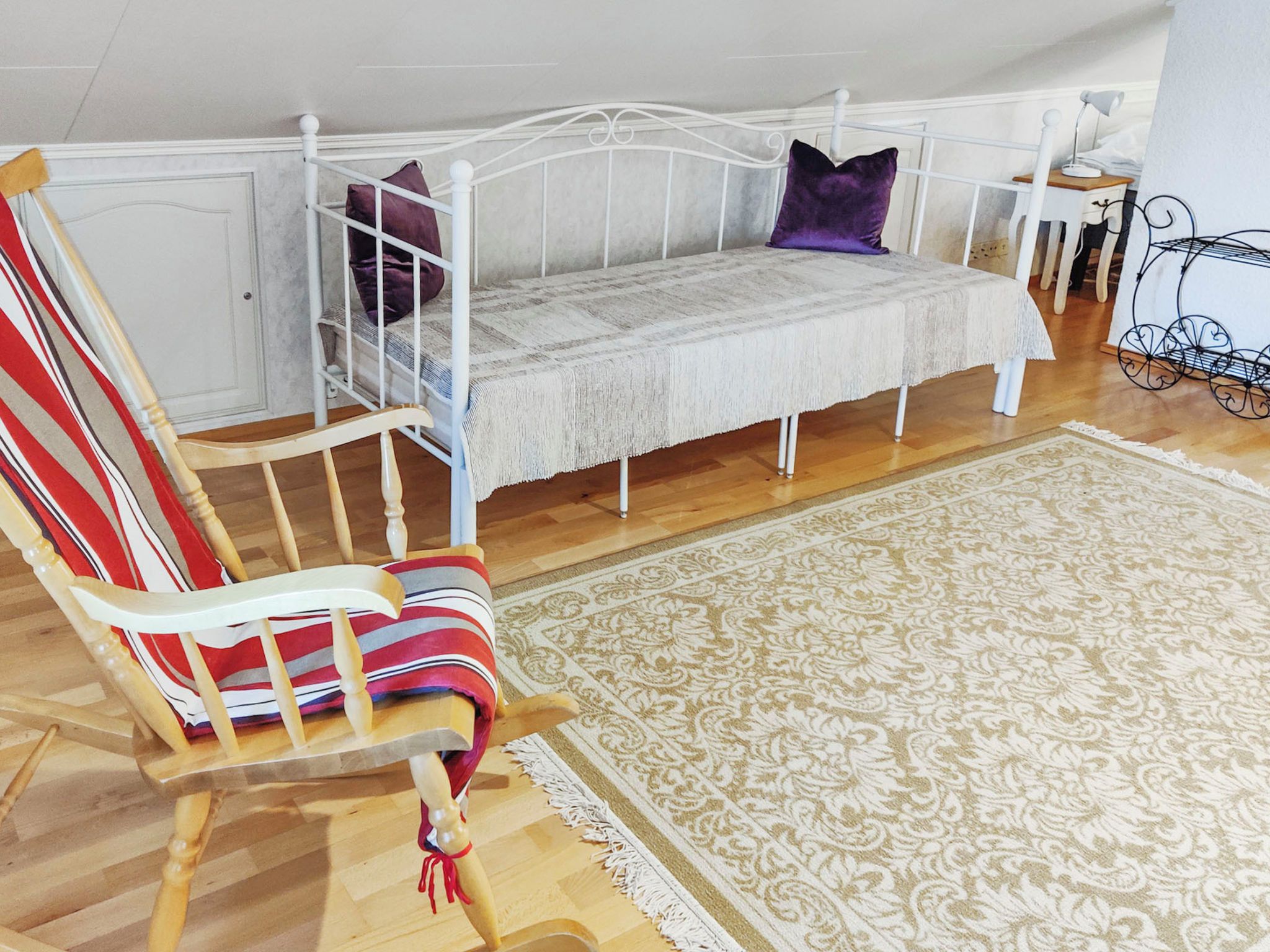 Une chambre avec un lit superposé, une chaise à rayures et un tapis à motifs.