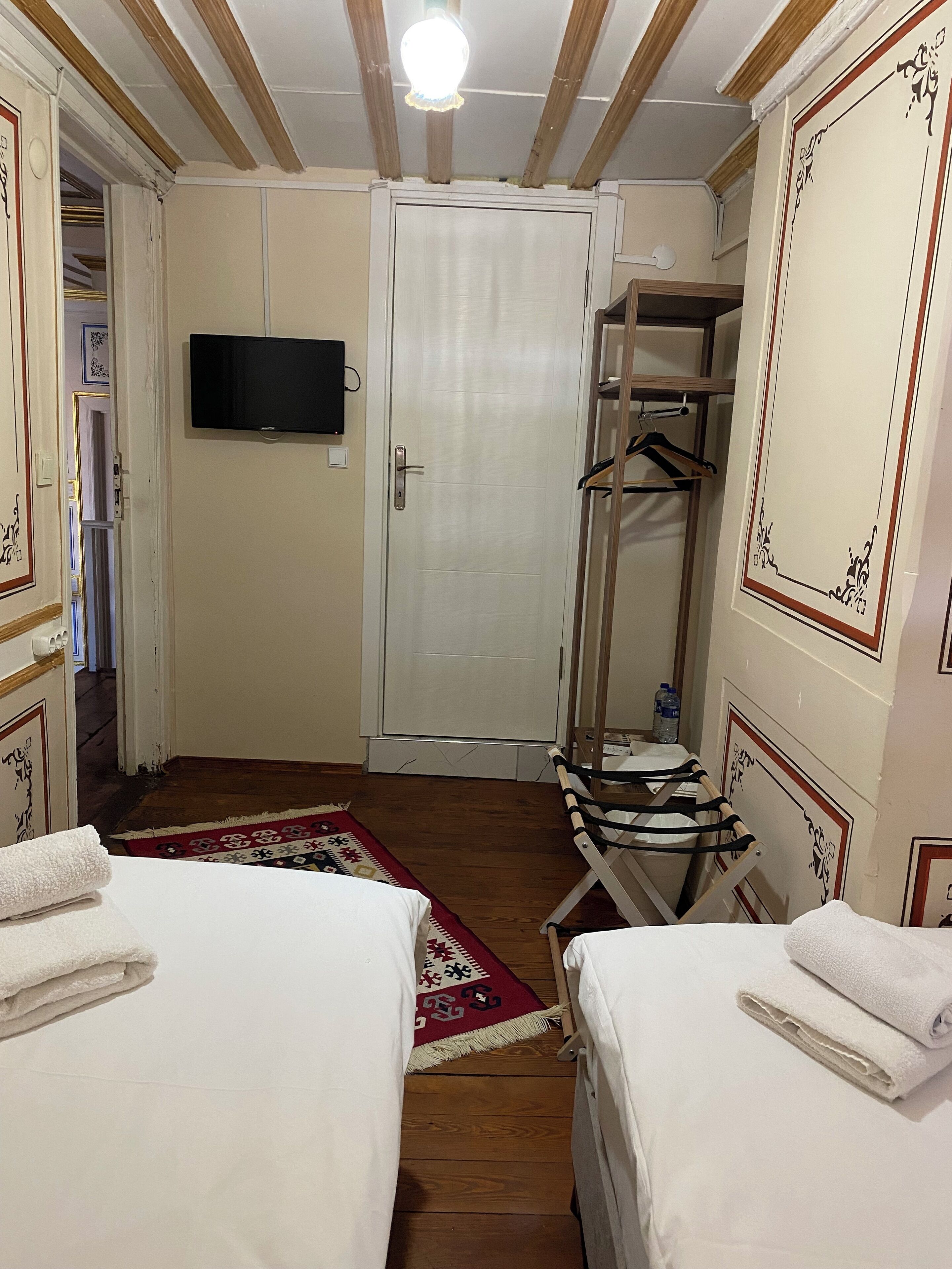 Habitación de hotel con dos camas, televisor, armario y espejo.