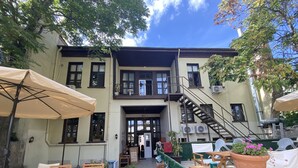A courtyard with outdoor seating, a staircase, and a building with multiple windows and balconies. - Oasis Pansiyon (Edirne)