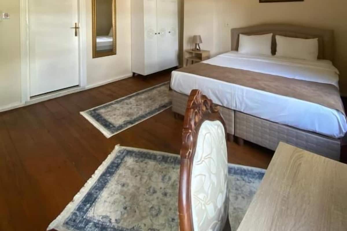 A bedroom with a large bed, a nightstand, a wardrobe, and a door.
