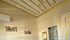 A bedroom with a large bed, a nightstand, a lamp, a chandelier, and two framed pictures on the wall. - Oasis Pansiyon (Edirne)