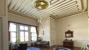 A spacious room with wooden flooring, a chandelier, and a dining area with a table and chairs. - Oasis Pansiyon (Edirne)