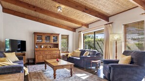 Ein Wohnzimmer mit Holzboden, einem Fernseher, einem Schrank und einem Sofa.