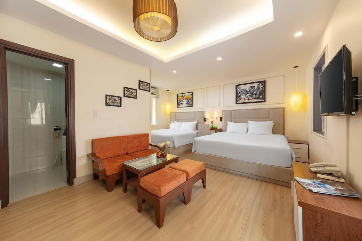 A hotel room with a bed, two sofas, a coffee table, a desk, and a TV.