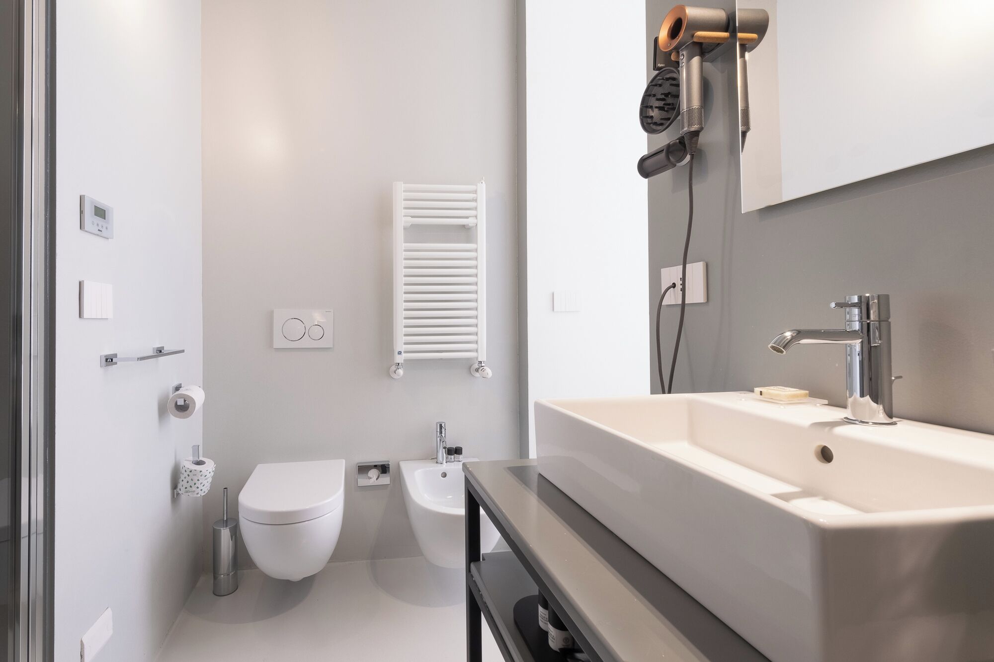 Un baño moderno con inodoro, bidé y un lavamanos grande con espejo.