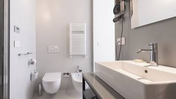 Un baño moderno con inodoro, bidé y un lavamanos grande con espejo.