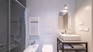 A modern bathroom with a glass shower enclosure, a bidet, a toilet, a sink, and a towel rack. - Oriana Homèl Torino (Turin)