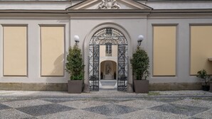 A building entrance with a decorative archway, potted plants, and a cobblestone pathway. - Oriana Homèl Torino (Turin)