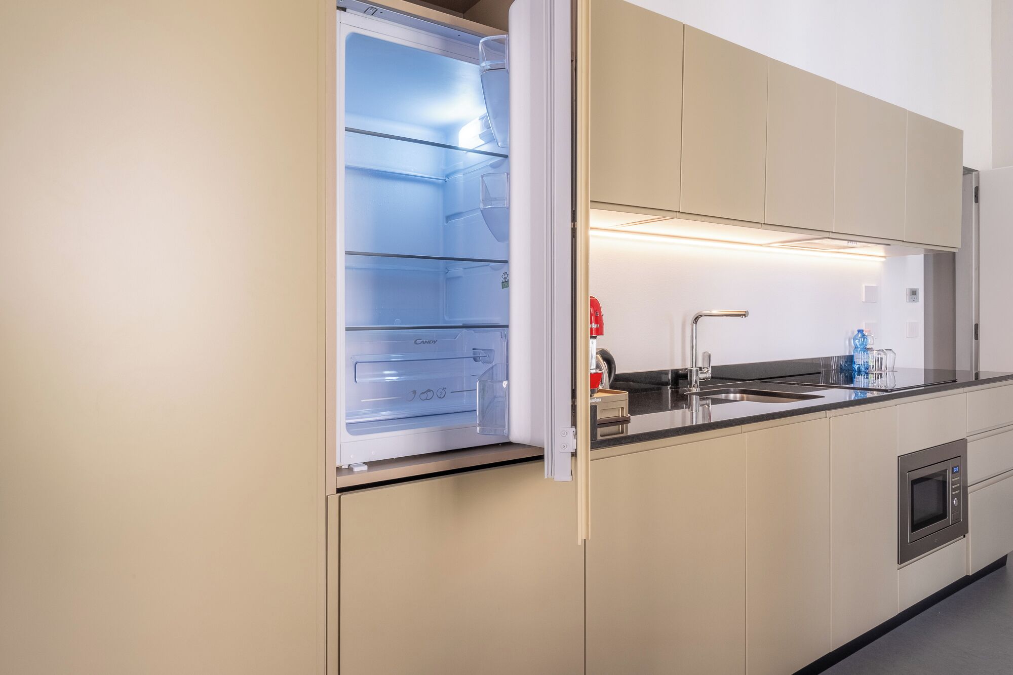 A modern kitchen with a built-in refrigerator, a sink, and a microwave.