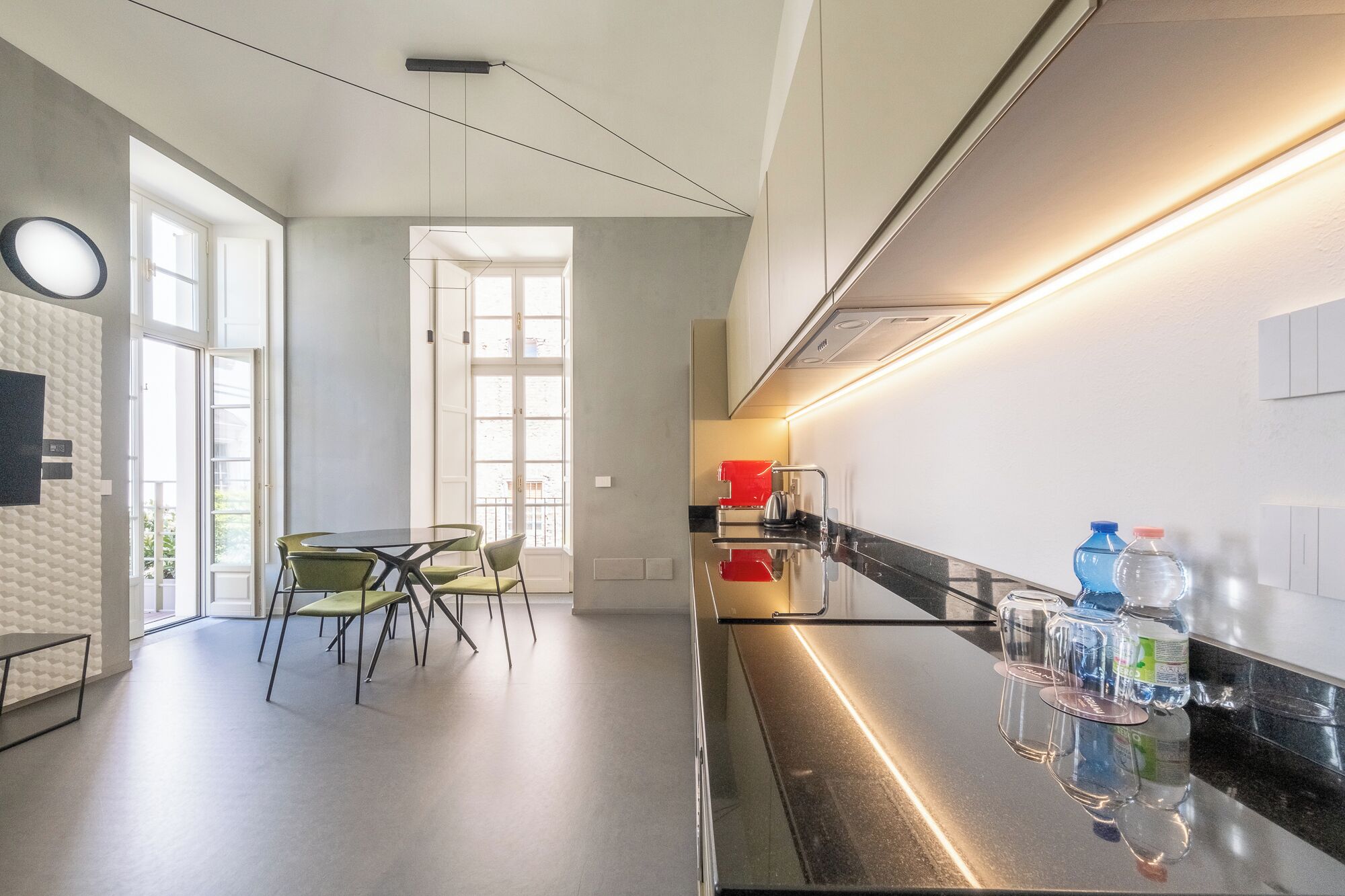 Una cocina moderna con encimera negra, electrodomésticos de acero inoxidable y ventana que proporciona luz natural.