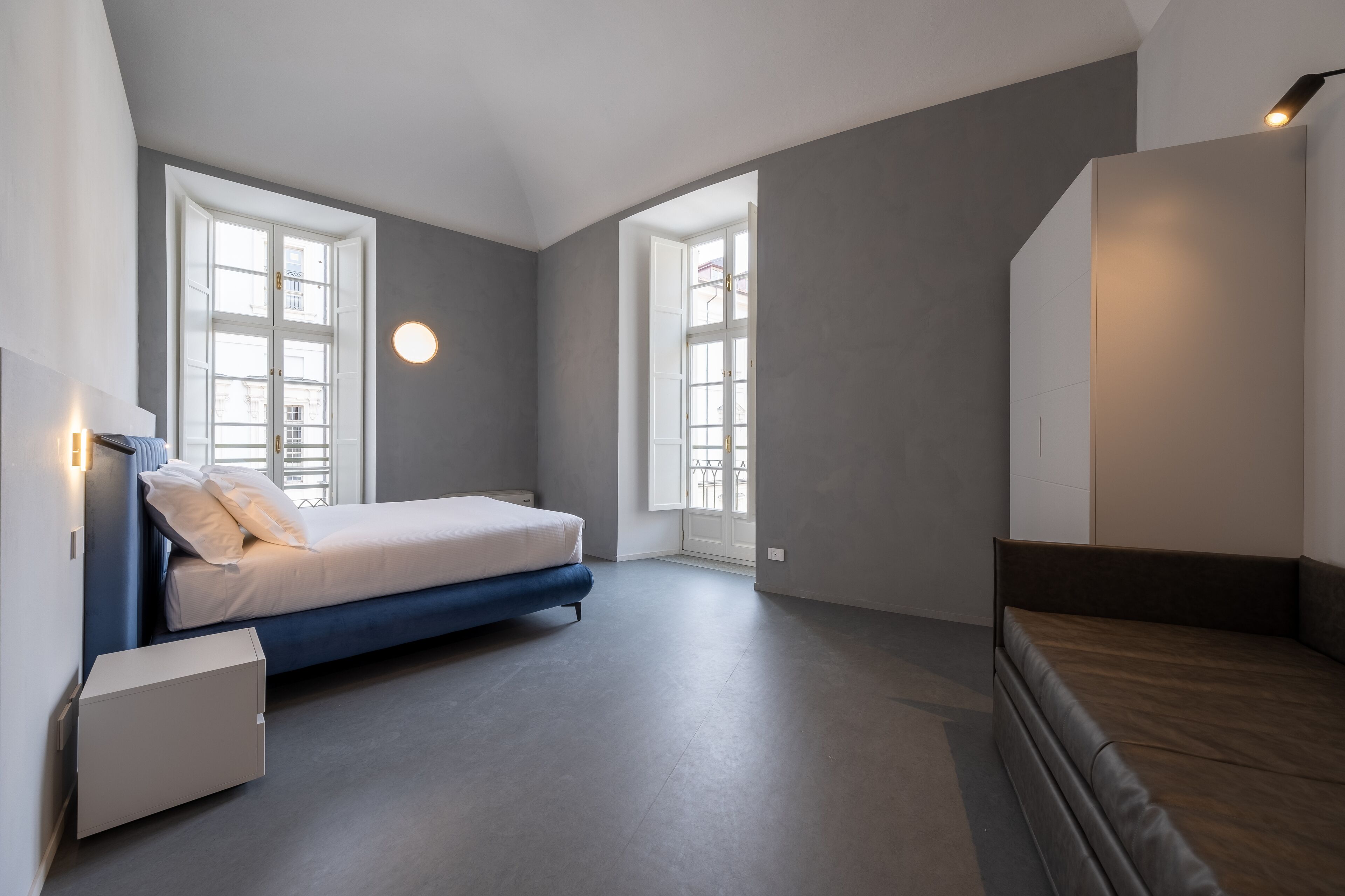 Un dormitorio moderno con una cama, un banco y un armario.