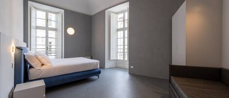 Un dormitorio moderno con una cama, un banco y un armario.