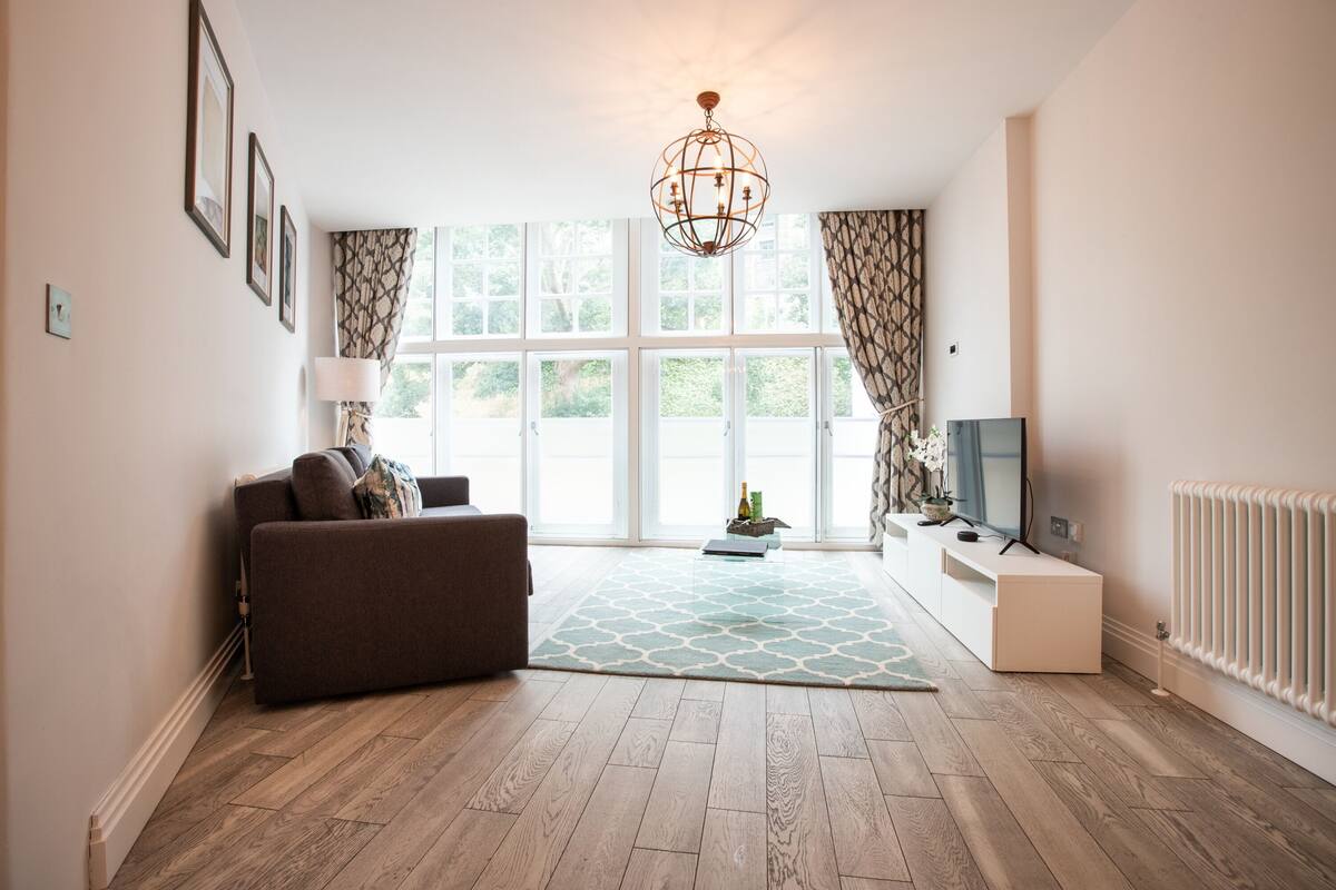 A living room with a sofa, a coffee table, a TV, and a radiator.