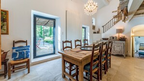 A dining area with a wooden table and chairs, a chandelier, and a staircase leading to an upper level. - Les Mas Ferrando Luberon: Beautiful authentic Mas Courroussouvo in Oppède-le-Vieux (Oppède)