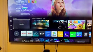 Ein Fernsehbildschirm zeigt eine Streaming-Dienstanwendung mit verschiedenen App-Symbolen und einem Banner mit der Aufschrift 'Kostenlos in VIDAA Kids ansehen'.