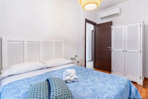 Une chambre à coucher avec un lit, une tête de lit blanche, une armoire blanche et une porte donnant sur une autre pièce.