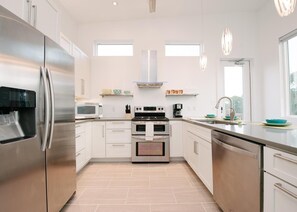 A modern kitchen with stainless steel appliances, white cabinetry, and a tiled floor. - Pet-Friendly Retreat Near the Beach (Cape San Blas)