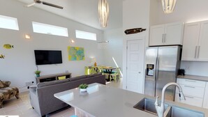 Una cocina moderna con una isla central, electrodomésticos de acero inoxidable y un comedor con sillas amarillas.