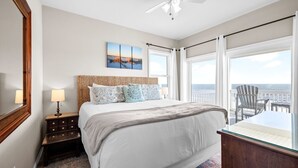 A bedroom with a bed, a nightstand, a lamp, a painting, a ceiling fan, and a balcony with a chair. - Gulf-Front Estate with Private Pool (Indian Pass)