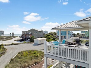 A beachfront property with a covered deck, a small pool, and a view of the ocean.