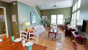 A spacious living room with a wooden dining table, striped sofas, and a television.
