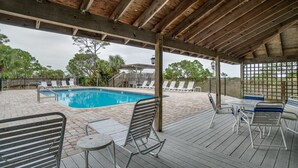 A covered outdoor pool area with lounge chairs and tables.