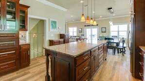 A spacious kitchen with wooden cabinets, a large island, pendant lighting, and a view to the dining area. - Family Beach Escape Near Gulf and Bay (Cape San Blas)