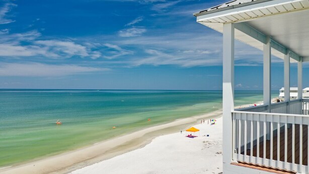 A beach view with a white building, clear blue sky, and calm sea. - Family Beach Escape Near Gulf and Bay (Cape San Blas)