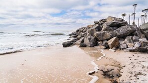 Ein Strand mit großen Felsen und sandigem Ufer.