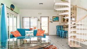 Ein Wohnzimmer mit einem blauen Sofa, einem Glastisch und einer Wendeltreppe.
