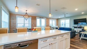 Una cocina amplia con una isla grande, detalles de madera e iluminación colgante.