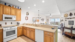 A modern kitchen with wooden cabinets, a built-in microwave, and a dishwasher. - Gulffront | Pool Access |  Salinas Park (Cape San Blas)