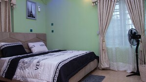 A bedroom with a bed, a standing fan, and a picture of the Eiffel Tower on the wall. - Tastefully furnished 2 bedroom apartment with 24/7 Power|WiFI|Security (Alimosho)