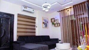 A modern living room with a sectional sofa, a round coffee table, and a decorative curtain. - Tastefully furnished 2 bedroom apartment with 24/7 Power|WiFI|Security (Alimosho)