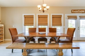 Un coin repas avec une table en bois, six chaises et un lustre.