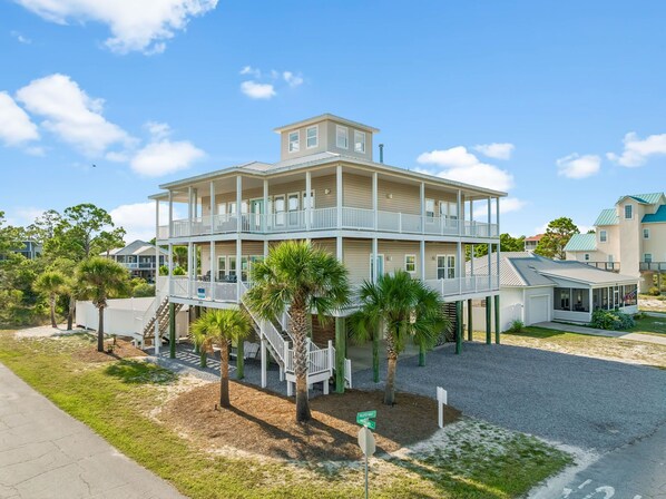 A multi-story building with a balcony on the second floor, a covered porch on the ground floor, and a flag on the right side.