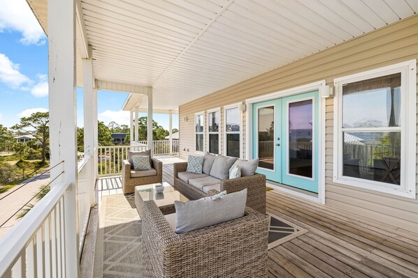 A covered porch with wicker furniture and a view of the neighborhood.