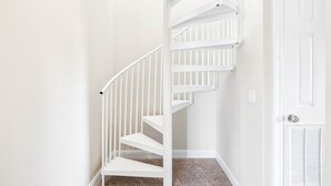 Una escalera interior blanca con barandilla y escalones alfombrados.