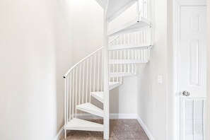 A white interior staircase with a handrail and carpeted steps.