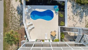 Vista aérea de una zona de piscina con sillones reclinables y una terraza de madera.