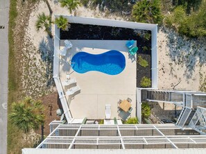 An aerial view of a swimming pool area with lounge chairs and a wooden deck.