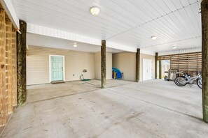 Amplo espaço interno com piso de concreto, pilares de madeira e porta de garagem.
