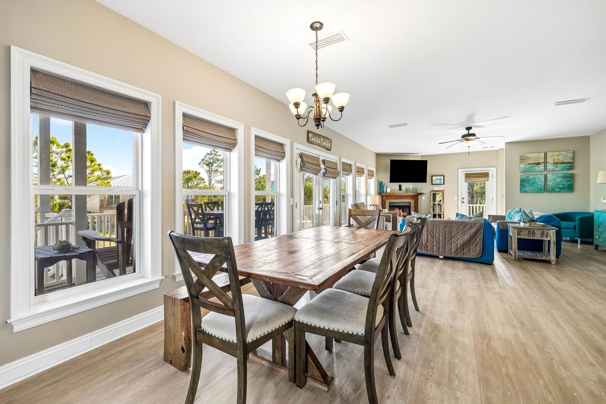 A spacious living area with a dining table, chairs, a fireplace, a TV, and a balcony with outdoor furniture.