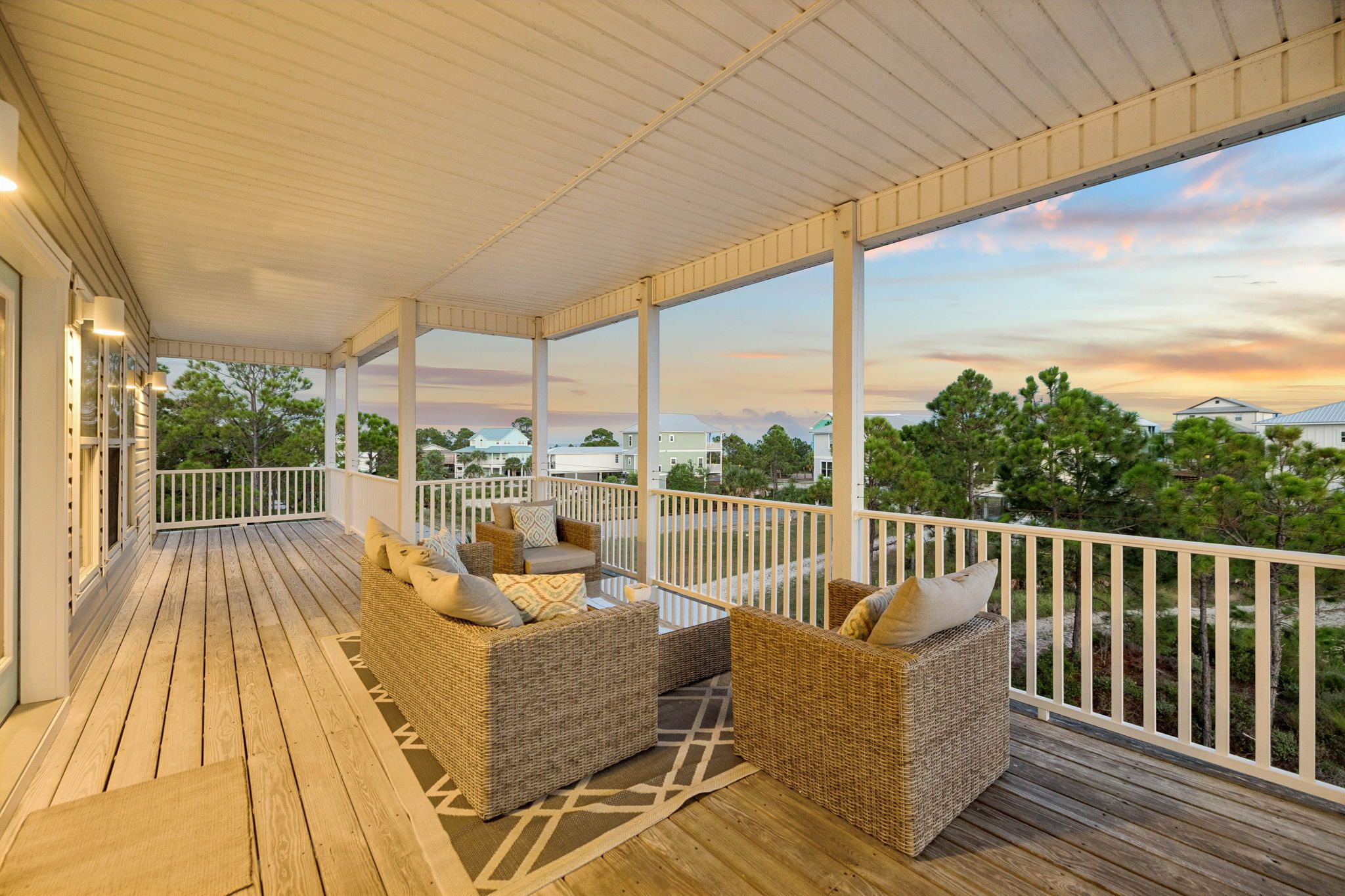 A covered outdoor seating area with wicker furniture and a view of the landscape.