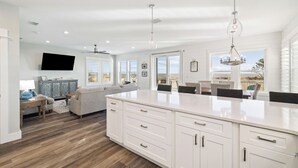A spacious kitchen with a large island, white cabinetry, and a view to the outside.