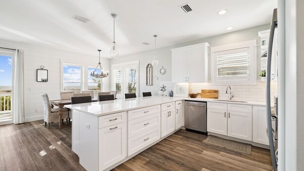 A modern kitchen with white cabinetry, a large island, and a view to the outside.